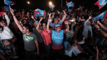 Opposition party supporters cheer and wave their party flags after Mahathir claimed victory.