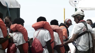 Migrants are transferred from the Aquarius to an Italian coast guard vessel at sea so they can be taken to Spain.