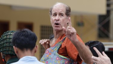 Australian filmmaker James Ricketson gestures as he is escorted by prison guards at the Cambodian Supreme Court in Phnom Penh, Cambodia.