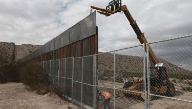 Workers raise the fence separating the towns of Anapra, Mexico, and Sunland Park, New Mexico, US, in November.