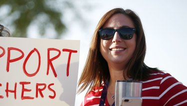 Stefanie Lowe, a teacher at Tuscano Elementary School, smiles as she joins other teachers, parents and students as they stage a "walk-in" for higher pay and school funding in Phoenix. 