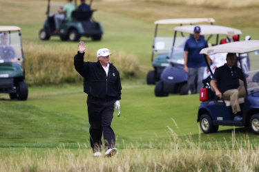 Trump waves to protesters while playing golf. 
