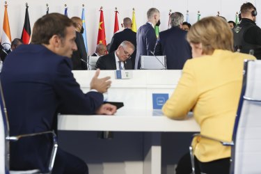 Prime Minister Scott Morrison sits across the table as Emmanuel Macron chats with German Chancellor Angela Merkel at the G20 in Rome.