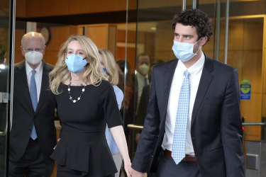 Former Theranos CEO Elizabeth Holmes, left, with her partner, Billy Evans, right, leaves the courthouse in San Jose, California on December 21, 2021. 