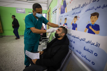 A health worker takes a nasal swab sample from a patient to test COVID-19 in Gaza. 