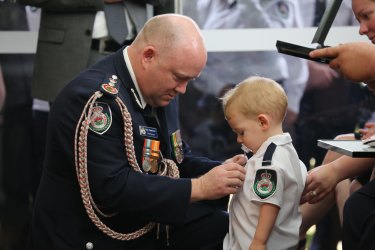 RFS Commissioner Shane Fitzsimmons pins the service medal of Geoffrey Keaton onto his son, Harvey.