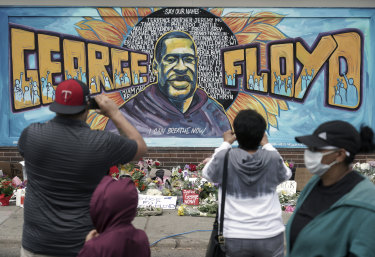 People gather at a memorial mural outside the store where George Floyd died.