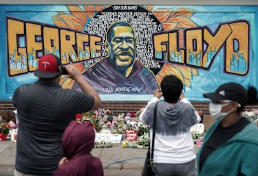 People gather at a memorial mural outside the store where George Floyd died.