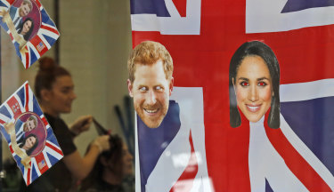 A woman gets a haircut as the Windsor shop window is decorated with flags and pictures of Prince Harry and Meghan Markle.