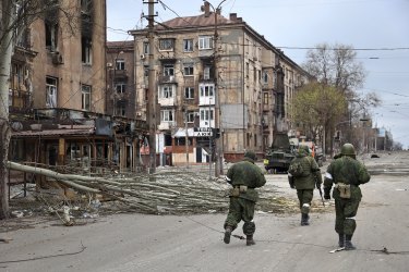 Servicemen of the militia from the Donetsk People’s Republic walk past damaged apartment buildings near the Mariupol plant.