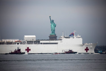 The US Navy hospital ship Comfort passes in front of the Statue of Liberty as it arrives in New York.