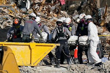 Search and rescue personnel remove remains on a stretcher.