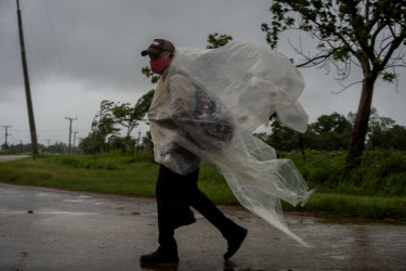 A man uses pieces of plastic to protect against the rain caused by Hurricane Ida.