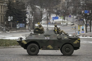 Ukrainian servicemen ride on top of an armoured personnel carrier speeding down a deserted boulevard during an air raid alarm in Kyiv.