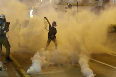 A protester throws back a tear gas canister during a confrontation with police.