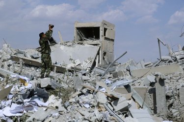 A Syrian soldier films the damage of the Syrian Scientific Research Centre.