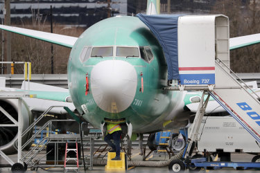 A worker looks underneath a Boeing 737 MAX jet.