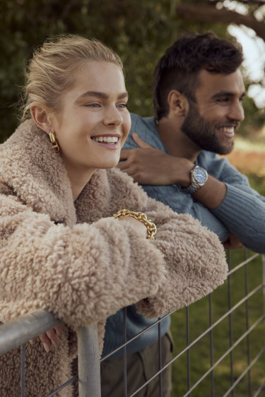 She wears: Friends with Frank “Henrietta” coat, $459; Oroton “Alexa” earrings, $120, and “Maisie” bracelet, $250. He wears: Polo Ralph Lauren jumper, $229; and Omega watch, $9575.