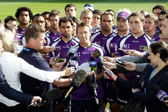 Solemn: Melbourne Storm coach Craig Bellamy speaks, surrounded by his players, after they were hammered by the NRL over the salary cap. 