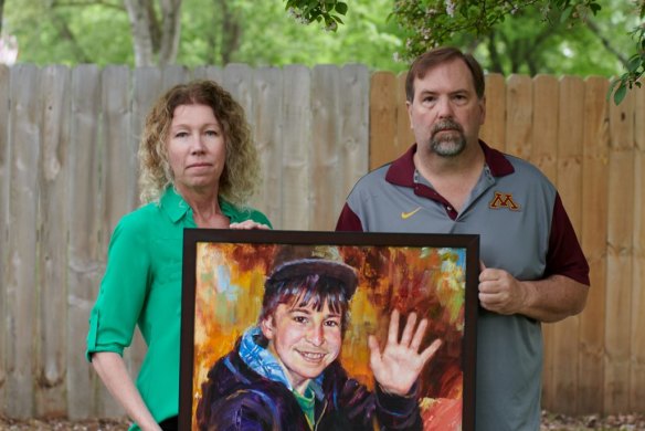 Melissa and Jim Crowley hold painted portrait of their son Alex Crowley, a Tartan student lost to brain cancer in 2012.