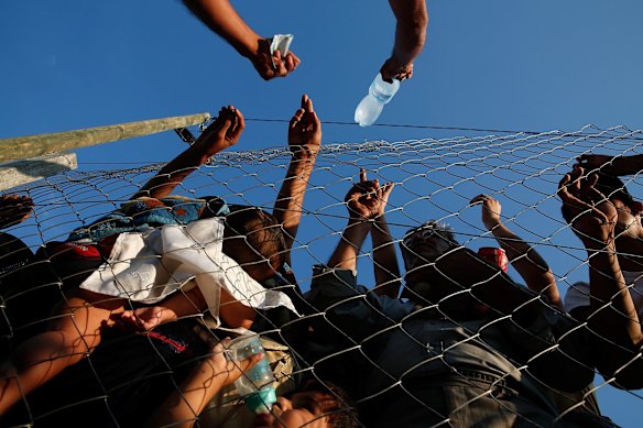 A Macedonian man sells water to migrants held inside a camp in Macedonia