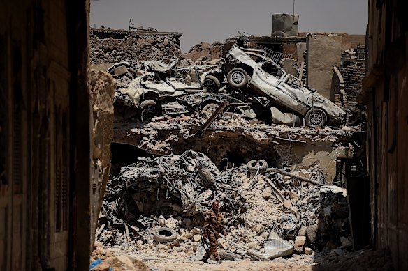 An Iraqi Special Forces soldier walks in front of a wall of debris on a road in West Mosul.