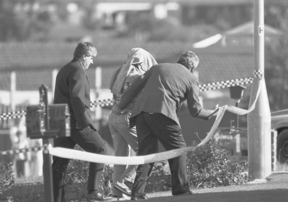 Detective Senior Sergeant Steve Leach, left, and other detectives take then prime suspect, the backpacker killer Ivan Milat into custody after raiding his home in Cinnabar Street, Eagle Vale. Taken on 22 May 1994.