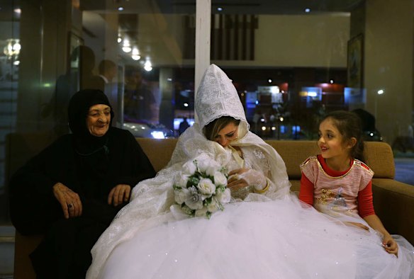 Rasha Kareem 24 (centre) shares a laugh with her new mother in law Hatheeya Yousif 81 (left) and neice after arriving at the Baghdad Hotel in the Al-Sadoon area of Baghdad, where she and her husband will spend their wedding night. Twenty two weddings arrived at the Baghdad Hotel for the evening.