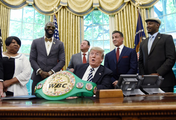 This image, in which Donald Trump signs an executive order granting a posthumous pardon for boxer Jack Johnson while Sylvester Stallone watches on, briefly features in the video.