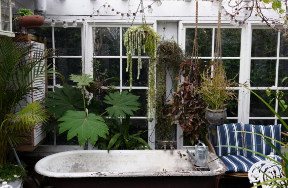 A ‘glasshouse’ fashioned with old windows features a functioning bath