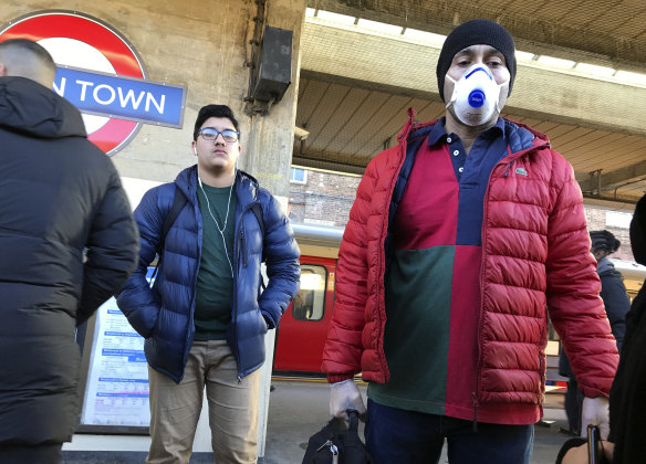 A commuter wears a face mask while waiting to catch the tube in London