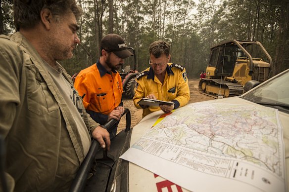 Property owner Brad Edge, Ben Donnelly and Group Captain Anthony Roberts from the RFS discuss the current fire map ahead of worsening weather conditions. They have been establishing fire breaks with tractors and dozers at Brads property in Congarinni near Macksville in northern NSW.