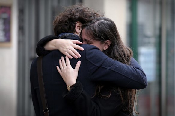 A couple embrace after laying flowers at the La Belle Equipe cafe in Paris.