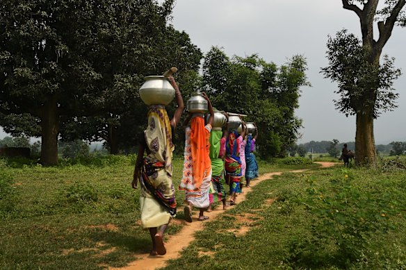 Women carry milk in pots in India's Chhattisgarh province, near Adani Mining's PEKB coal mine.