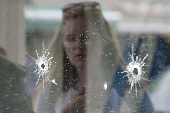 A woman looks at the bullet holes on the window of IV Deli Mark where Friday night's mass shooting took place by a drive-by shooter.