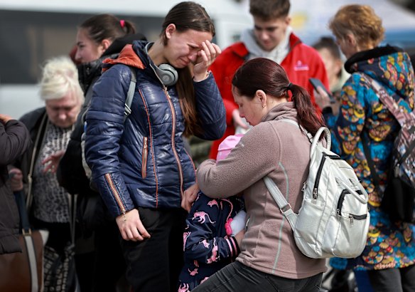 People fleeing from the eastern part of Ukraine become emotional as they wait for a bus that will take them to Poland from the central railway station in Lviv, Ukraine.