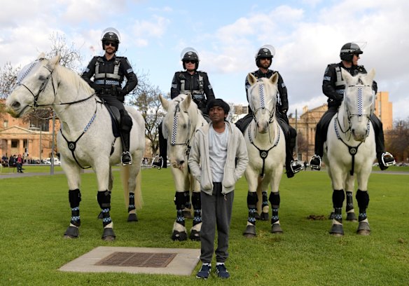 A child poses with police horses after a march in solidarity with protests in the United States on June 06, 2020 in Adelaide, Australia.