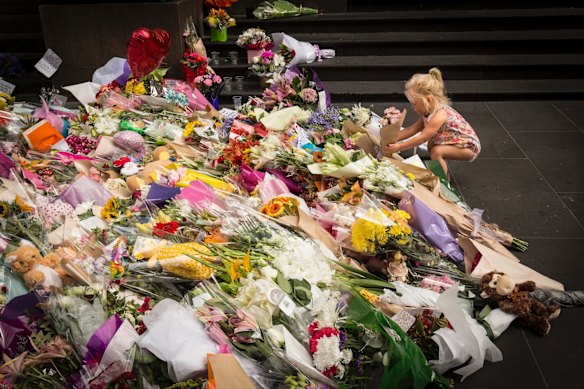 Two year old Jesse lays flowers at the floral tribute to the victims.