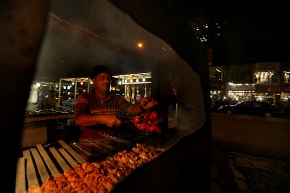 Hussein Jabar from Najaf cooks tomatoes and meat on a grill barbeque on Karada street in the Karada area of Baghdad.