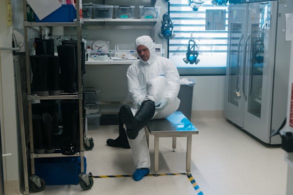 The lab’s head, Associate Professor Stuart Turville dresses up in extensive PPE gear within the second chamber of the PC3 lab.