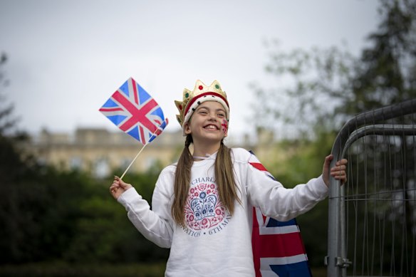 A girl wearing a crown waves a Union flag as she watches the coronation parade on the Mall in London.