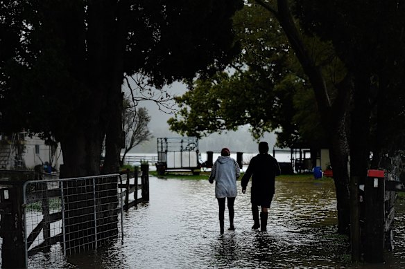 Amanda and Greg Soper walk through the floodwaters on their property at Shoalhaven Heads, NSW.
