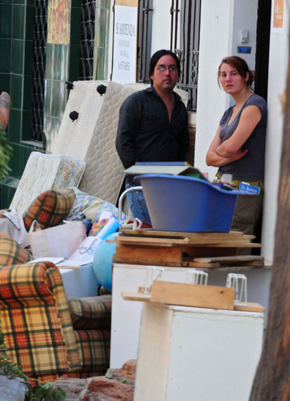 Two people look at their belongings placed outside their house in Santiago.