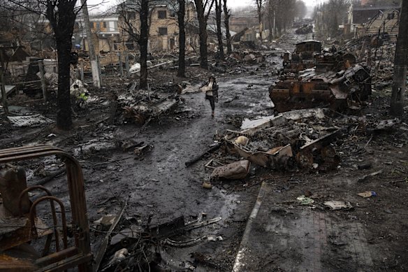 A woman walks between destroyed Russian tanks in Bucha, on the outskirts of Kyiv.