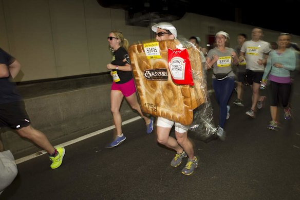 City 2 Surf:  A man dressed up as a pie amongst the City2Surf runners making their way through William Street tunnel.