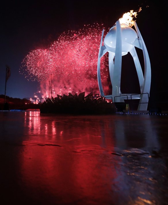 Fireworks explode behind the Olympic flame during the opening ceremony of the 2018 Winter Olympics in Pyeongchang, South Korea.