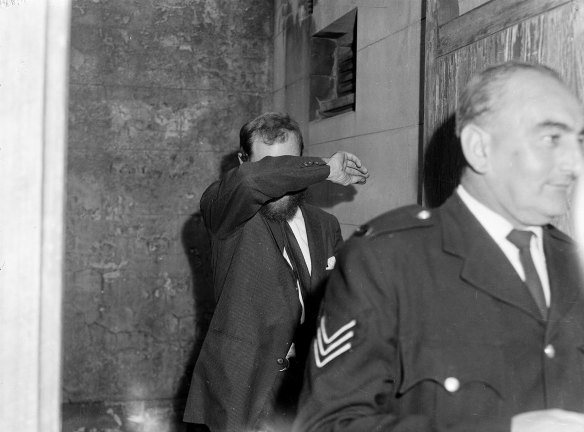 Mr Geoffrey Chandler covers his face as he arrives at Central Court, Sydney, on 23 May 1963. 