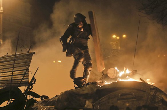 An anti-government protester runs during clashes with riot police in Kiev's Independence Square, the epicenter of the country's current unrest,  Kiev, Ukraine, Tuesday, Feb. 18, 2014. Thousands of police armed with stun grenades and water cannons attacked a large opposition camp in Ukraine's capital on Tuesday that has been the center of nearly three months of anti-government protests after at least nine people were killed in street clashes.