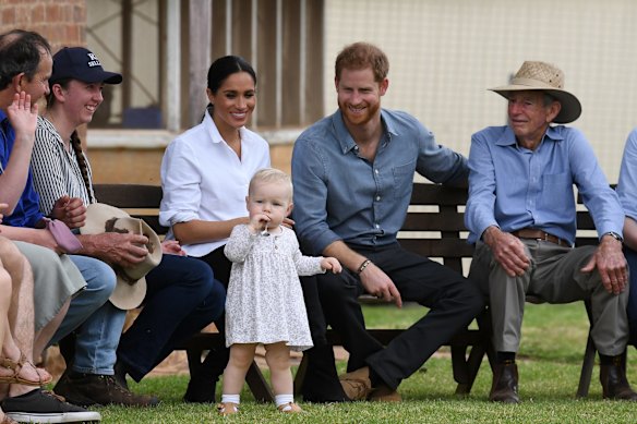 Thirteen-month-old Ruby Carroll is watched by Prince Harry and Princess Meghan during morning tea at a drought-affected farm in Dubbo.