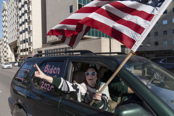 A Biden supporter cheers while driving past a Trump rally protesting the election results.